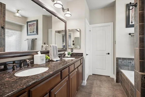 a bathroom with a sink double vanity granite tub shower and a mirror