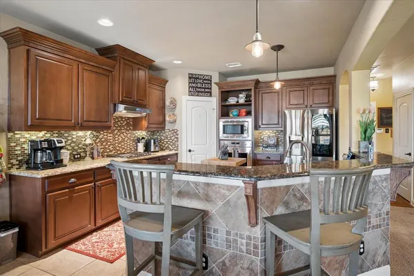 a kitchen with granite countertop a stove a sink a dining table and chairs
