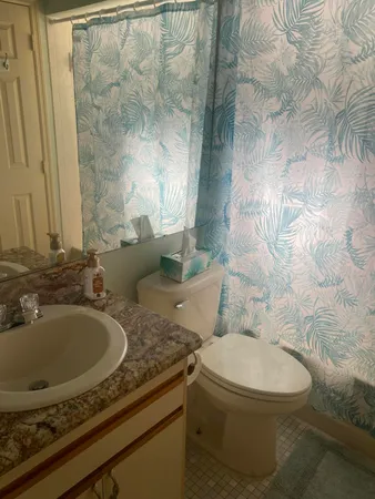 a bathroom with a granite countertop sink a toilet and a mirror