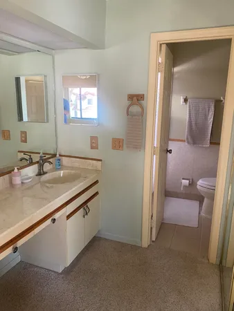 a bathroom with a granite countertop sink a toilet a shower and a mirror