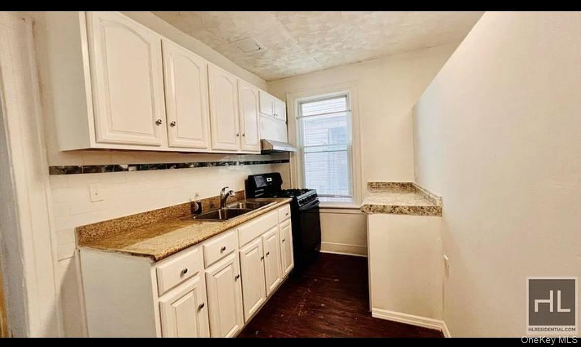175-08 93rd Avenue Queens, NY 11433 - Photo 7 of 17 a kitchen with stainless steel appliances granite countertop a stove a sink and a refrigerator with wooden floor