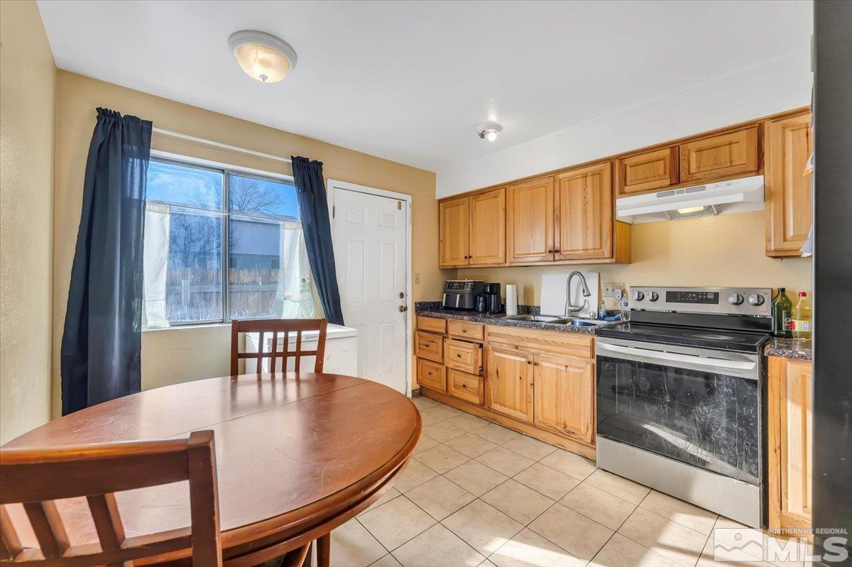 1402 East 9th Street, Unit 11 Reno, NV 89512 - Photo 12 of 25 a kitchen with granite countertop a stove a sink a dining table and chairs