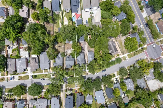 an aerial view of residential houses with outdoor space and trees all around