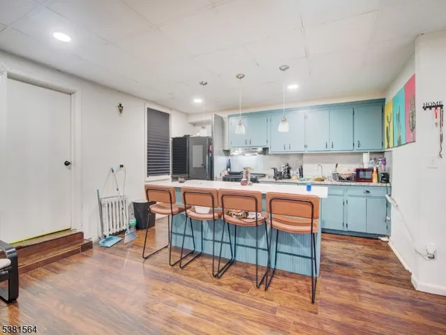 a kitchen with stainless steel appliances granite countertop a sink a stove a refrigerator and island with wooden floor