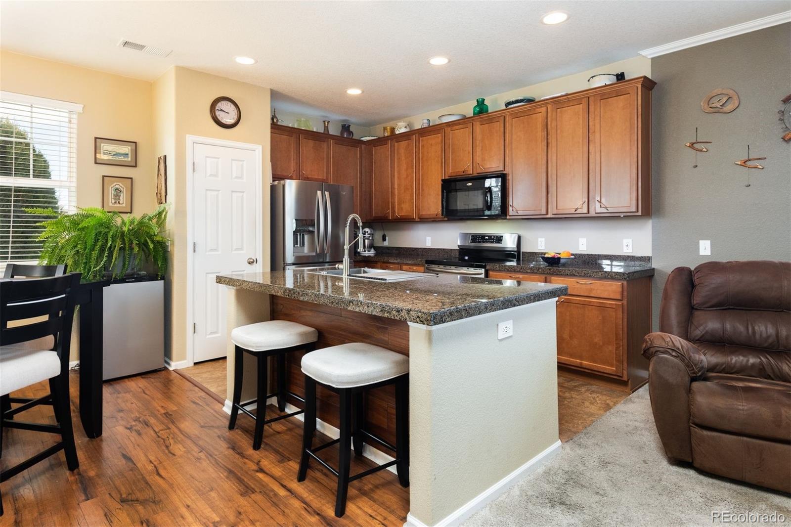 3661 South Perth Circle, Unit 6101 Aurora, CO 80013 - Photo 12 of 48 a kitchen with stainless steel appliances granite countertop a refrigerator a sink a stove a dining table and chairs