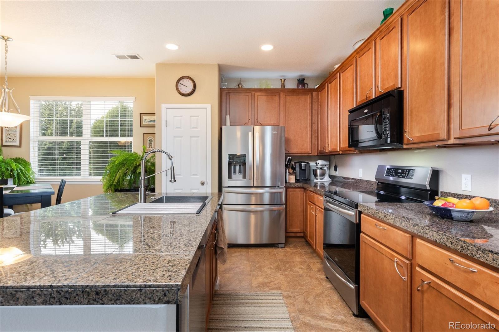 3661 South Perth Circle, Unit 6101 Aurora, CO 80013 - Photo 13 of 48 a kitchen with stainless steel appliances granite countertop a refrigerator a stove a sink and a microwave