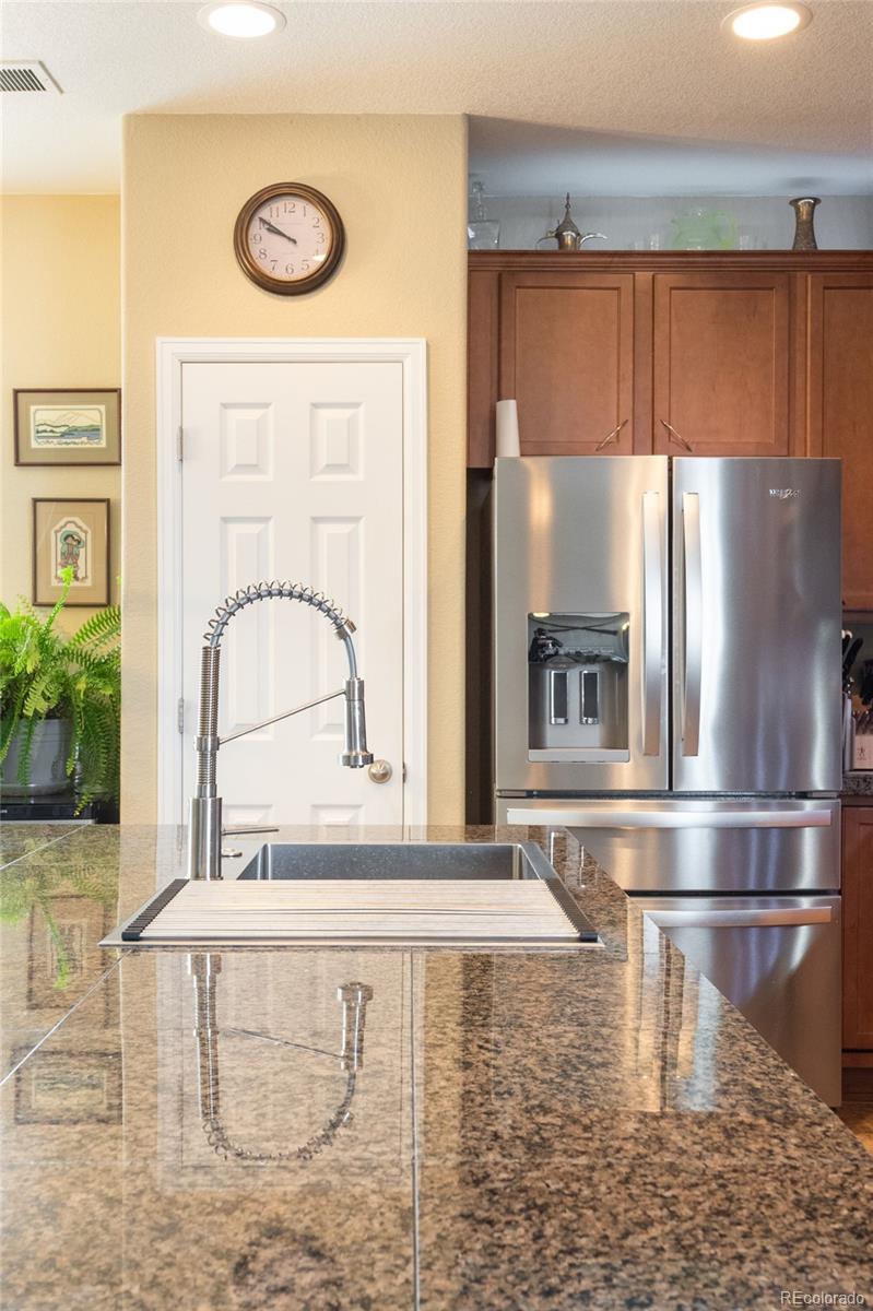 3661 South Perth Circle, Unit 6101 Aurora, CO 80013 - Photo 14 of 48 a kitchen with kitchen island a stove a refrigerator and a cabinets with wooden floor