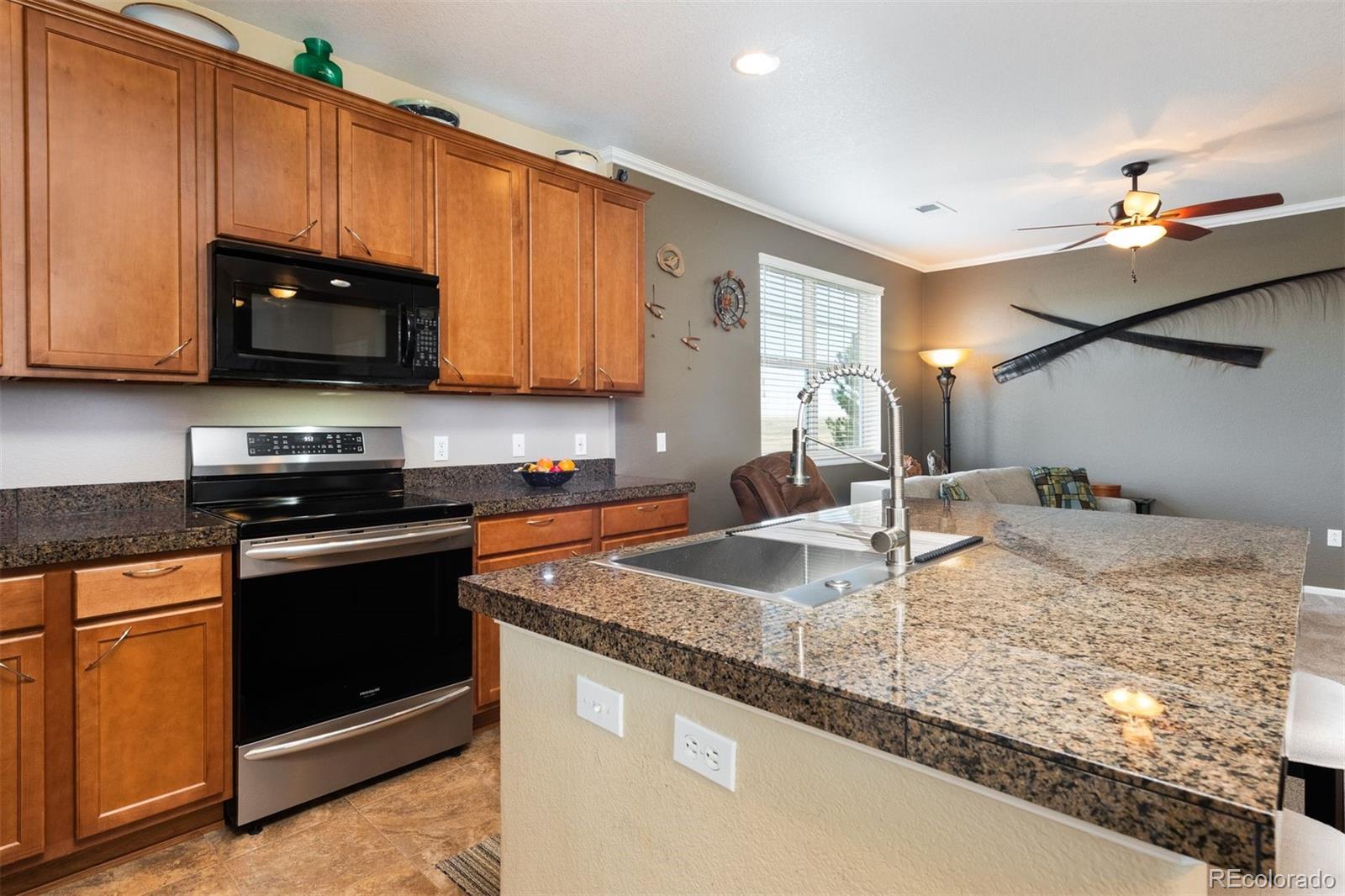 3661 South Perth Circle, Unit 6101 Aurora, CO 80013 - Photo 16 of 48 a kitchen with granite countertop a sink a stove and a microwave