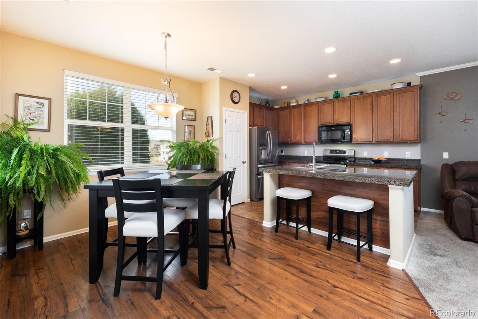 3661 South Perth Circle, Unit 6101 Aurora, CO 80013 - Photo 9 of 48 a kitchen with kitchen island granite countertop wooden floor cabinets and dining table chairs