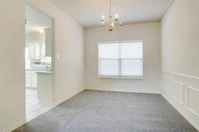 an empty room with chandelier fan and windows