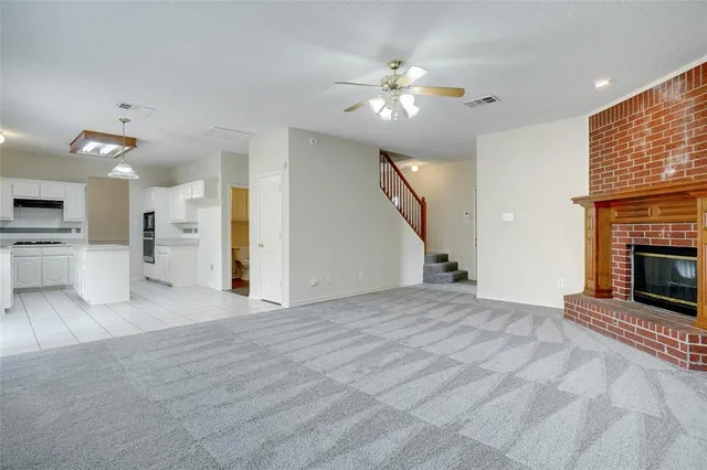 an empty room with chandelier fan and windows