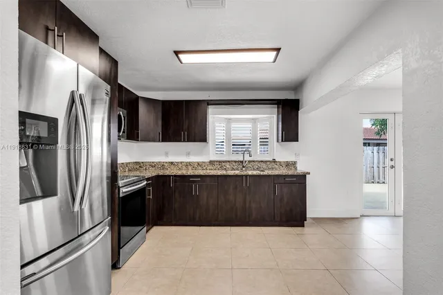 a kitchen with granite countertop a refrigerator and a sink
