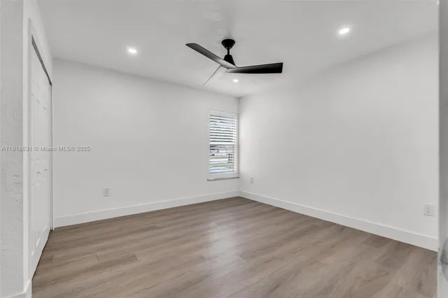 a view of empty room with wooden floor and fan