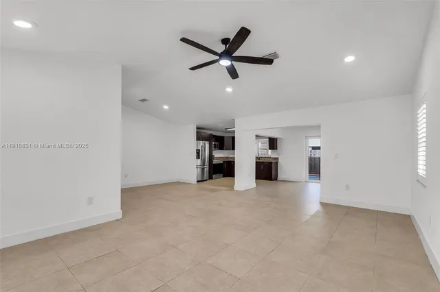 an empty room with ceiling fan and windows