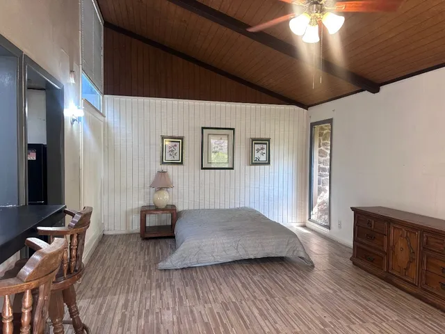 a spacious bedroom with a bed and wooden floor