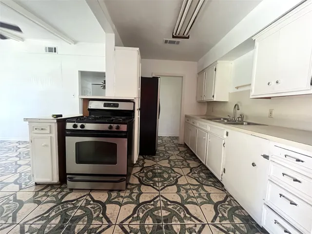 a kitchen with granite countertop a stove sink and cabinets