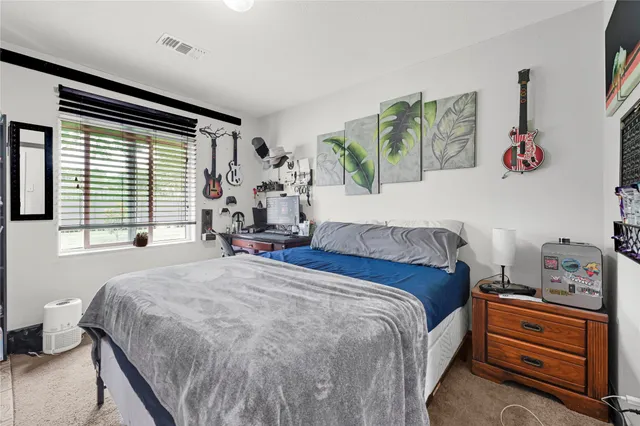 a bedroom with a bed and a dresser next to a window