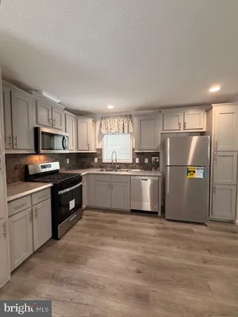 a kitchen with granite countertop a refrigerator a sink dishwasher a stove top oven a refrigerator with cabinets and wooden floor