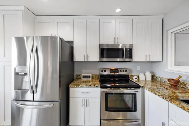 a kitchen with stainless steel appliances a stove a sink refrigerator and microwave