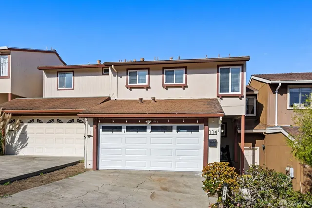 a view of a white house with large windows and potted plants