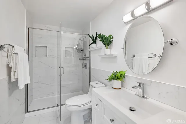 a bathroom with a shower a sink and a potted plant