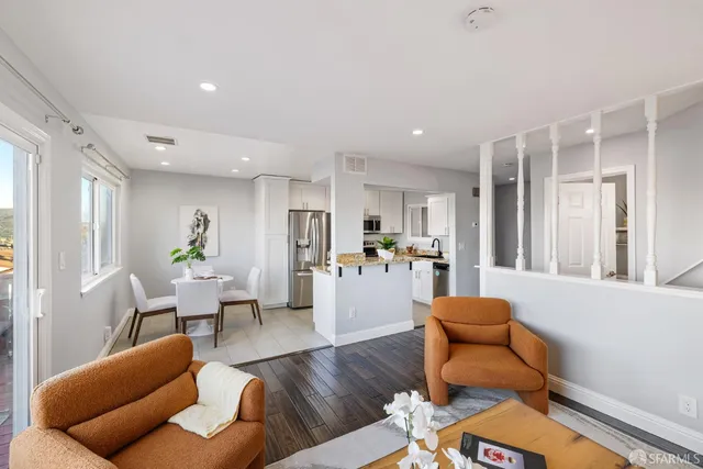 a living room with furniture kitchen view and a large window