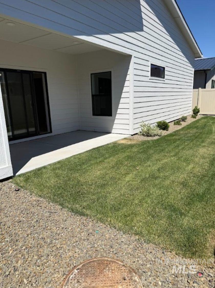 665 West Wrangler Street Meridian, ID 83646 - Photo 13 of 18 Covered patio area with white siding exterior, sliding glass door access, and a manicured lawn