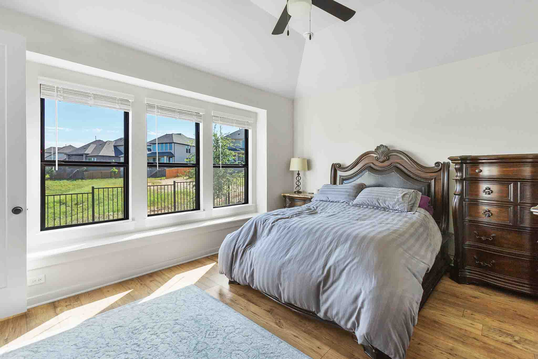 220 Basket Flower Loop Kyle, TX 78640 - Photo 16 of 40 A spacious bedroom provides a comfortable retreat with a vaulted ceiling and natural light from wide windows.