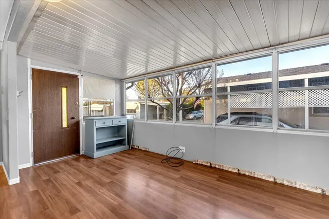 a view of empty room with wooden floor and kitchen view