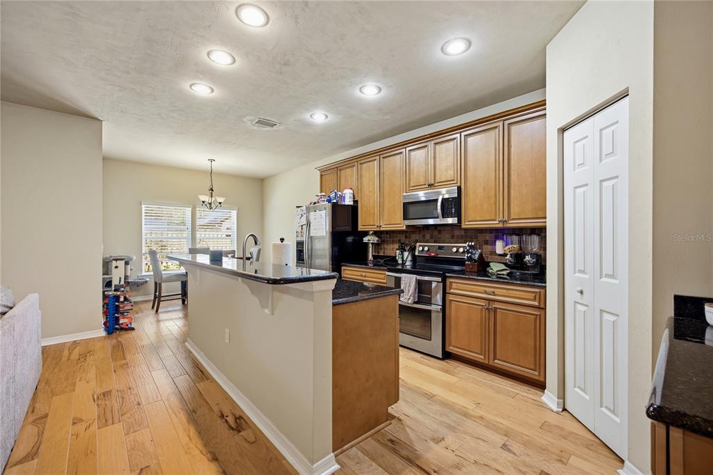7550 Southwest 81st Way Gainesville, FL 32608 - Photo 14 of 31 a kitchen with stainless steel appliances granite countertop a refrigerator oven a sink dishwasher and white cabinets with wooden floor