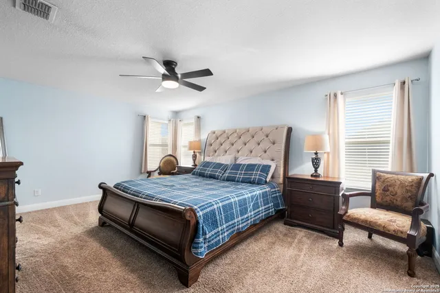 a bedroom with a bed a couch and a ceiling fan