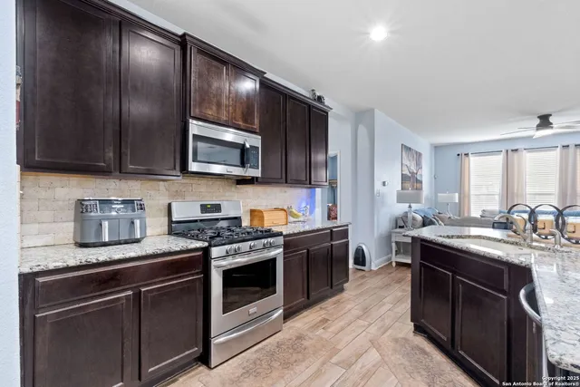 a kitchen with stainless steel appliances granite countertop wooden cabinets a stove top oven a sink and dishwasher