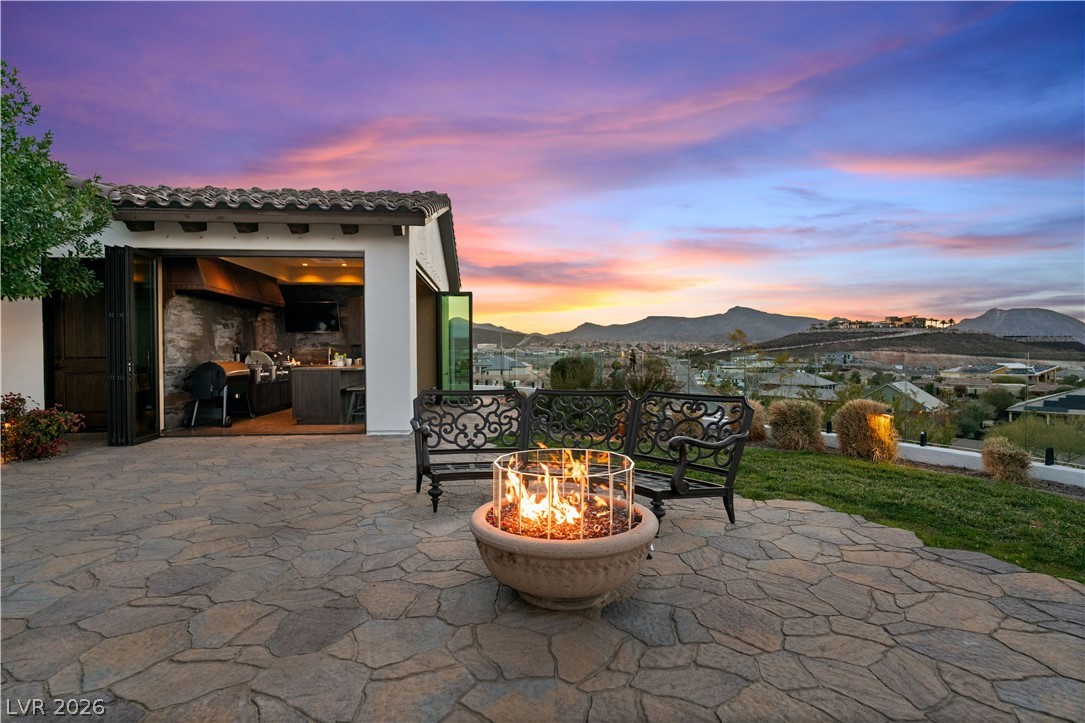 1123 Christian Road Henderson, NV 89002 - Photo 69 of 94 An inviting flagstone patio with a fire pit and panoramic mountain views, perfect for evening gatherings.
