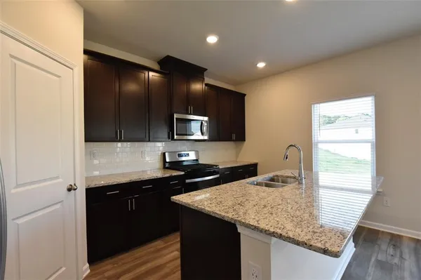 a kitchen with granite countertop kitchen island a sink appliances and cabinets
