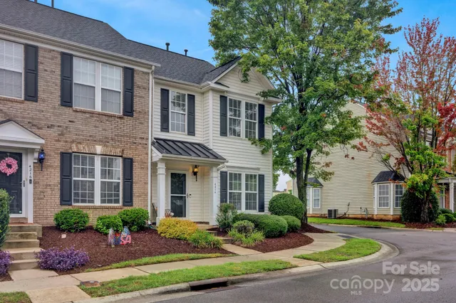 a view of a brick house with many windows plants and large tree