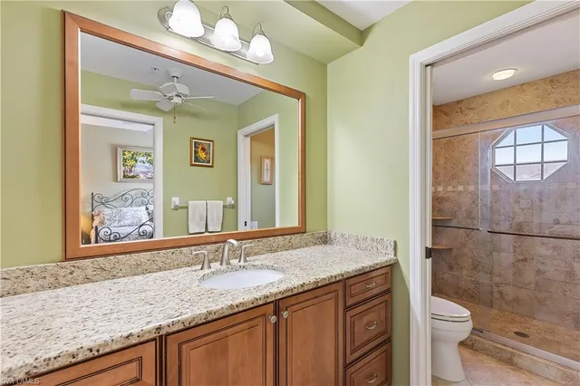 a bathroom with a granite countertop sink a toilet and a mirror