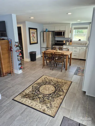 a living room with stainless steel appliances furniture a rug and a flat screen tv