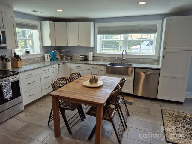 a kitchen with a table chairs stove a sink and dishwasher a refrigerator with wooden floor