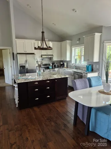 a kitchen with a dining table chairs sink and white cabinets