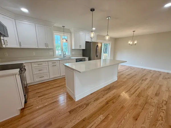 a large kitchen with stainless steel appliances a refrigerator a stove a sink dishwasher a oven and white cabinets with wooden floor