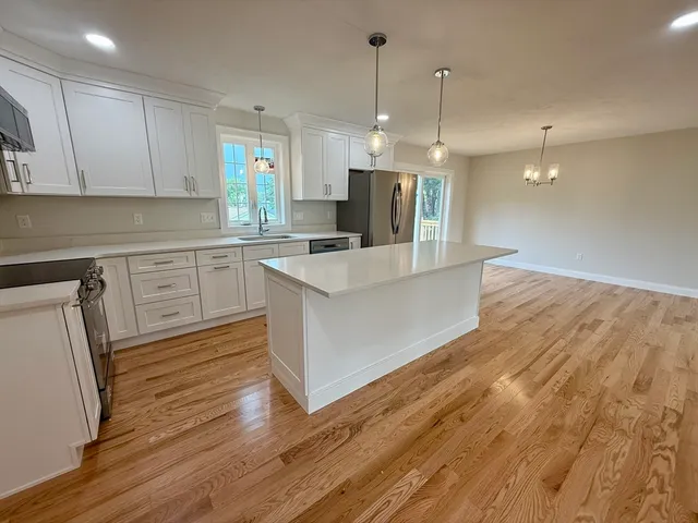 a large kitchen with stainless steel appliances a refrigerator a stove a sink dishwasher a oven and white cabinets with wooden floor