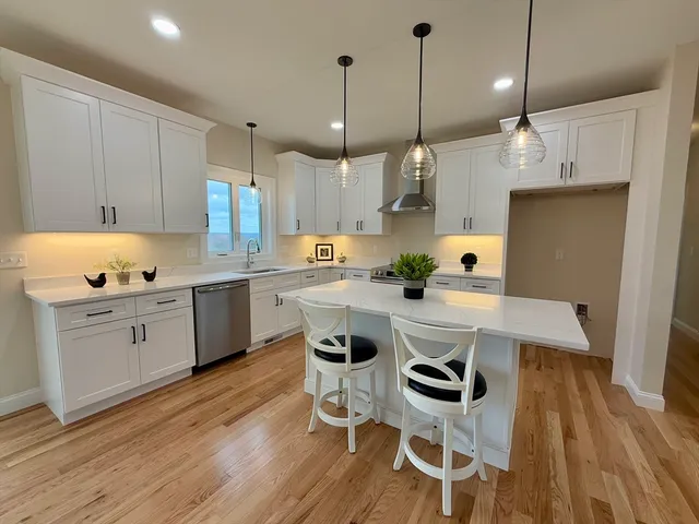 a kitchen with granite countertop a stove a sink a dining table and chairs