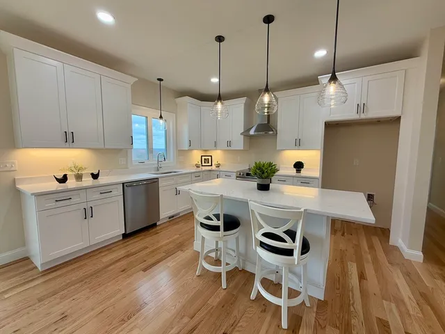 a kitchen with granite countertop a stove a sink a dining table and chairs