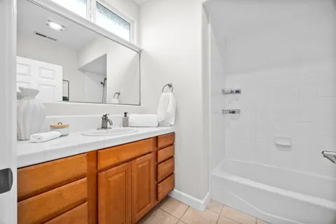 a bathroom with a sink double vanity granite tub shower and a mirror