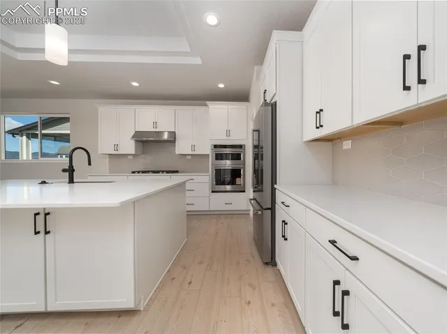 a kitchen with kitchen island granite countertop a sink cabinets and stainless steel appliances