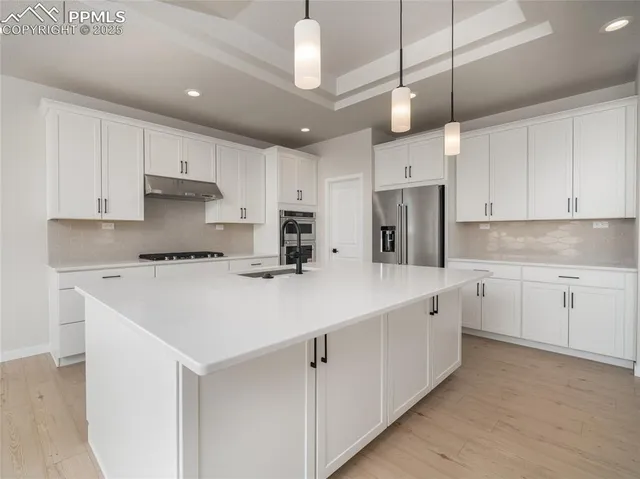 a kitchen with kitchen island a sink stainless steel appliances and white cabinets