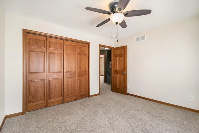 an empty room with closet and a ceiling fan