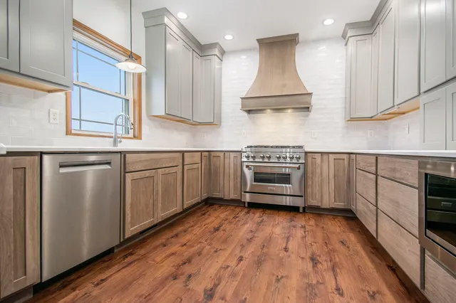 a kitchen with stainless steel appliances granite countertop a sink a stove and a wooden floors