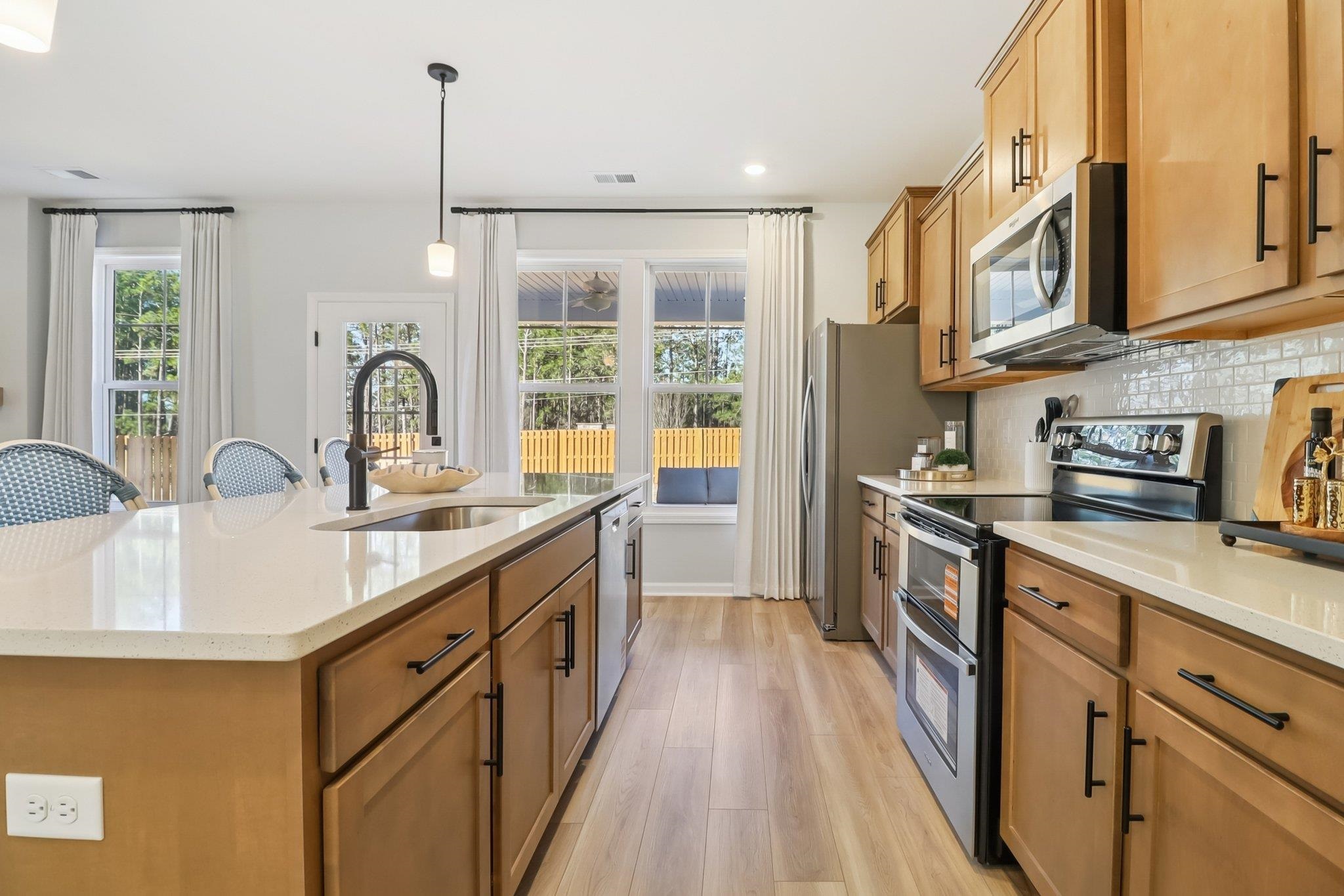 704 Bramble Way Conway, SC 29527 - Photo 3 of 17 Kitchen featuring appliances with stainless steel finishes, pendant lighting, an island with sink, backsplash, and light wood-style flooring