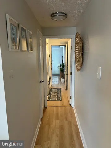 a view of a hallway with wooden floor and a bathroom